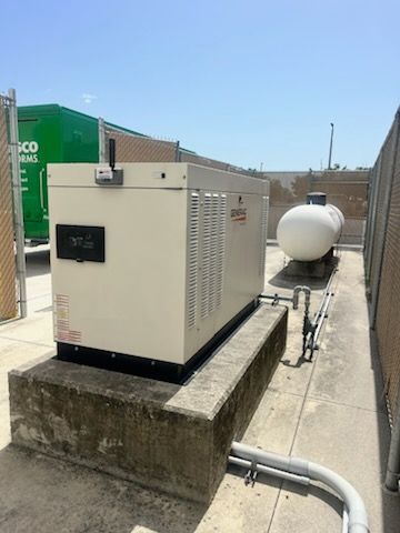 Liquid-cooled commercial generator on a concrete pad with its propane tank